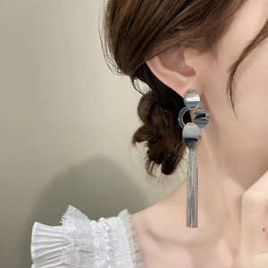 Elegant silver tassel drop earrings featuring layered geometric circular studs on model