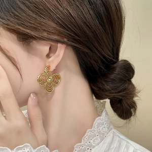Detailed view of golden multi-layer clover earrings on a model in white lace