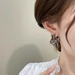 Detail of silver hollow floral earrings with layered circles and center crystal on model