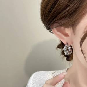 Detailed close-up of a silver twisted rope earring worn by a model in a minimalist style
