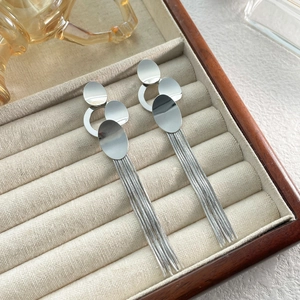 Detail of silver long tassel earrings with polished geometric oval plates in jewelry box