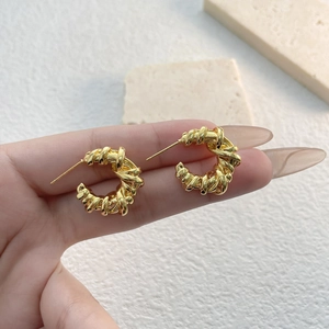 Vintage gold plated geometric woven C-shape hoop earrings shown held in hand