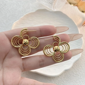 Chic hollow petal geometric earrings in gold with center bead on a ceramic display