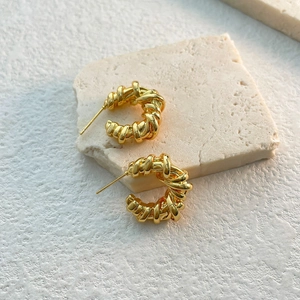 Detail of vintage gold-plated C-shaped earrings with textured woven metal design