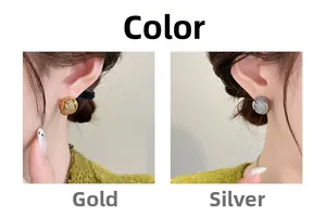 Détail de boucles d'oreilles sphériques texturées en or et argent sur mannequin