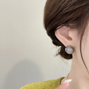 Gros plan d'une boucle d'oreille argentée avec texture grillagée et fini métallique