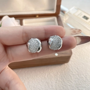 Gros plan de boucles d'oreilles boules en maille argentée à texture polie entre les doigts