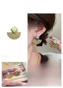 Détail des boucles d'oreilles éventail rétro avec motif écailles et carré argenté