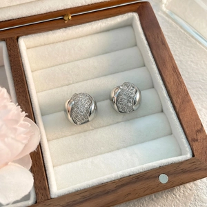Détail de boucles d'oreilles tissées ajourées dans un écrin à bijoux en bois chic