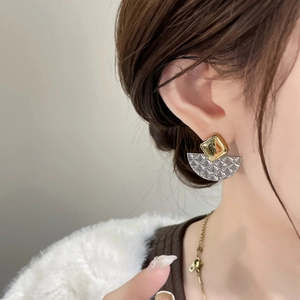 Détails de boucles d'oreilles géométriques bicolores avec texture ondulée sur un modèle