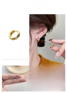Close-up of geometric faceted hoop earrings in gold and silver plating