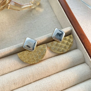 Détail de boucles d'oreilles vintage avec carré argenté et texture dorée en éventail
