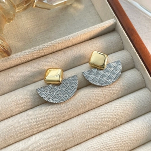 Gros plan de boucles d'oreilles en éventail avec carré doré et motif de vagues argenté