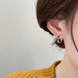 Close-up of geometric faceted hoop earring in silver finish on model ear