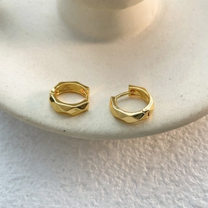 Macro detail of geometric 18K gold plated hoop earrings with irregular faceted textures