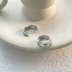Detail showing silver geometric faceted earrings with a 18k plated textured finish