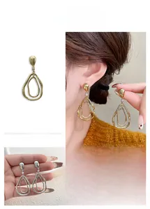 Détail de boucles d'oreilles doubles créoles irrégulières avec clou en zircone