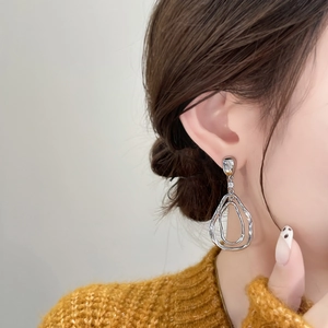 Gros plan de boucles d'oreilles pendantes en argent avec zircons sur un pull jaune