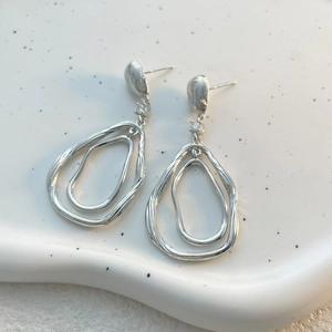 Vue macro des boucles d'oreilles goutte d'eau argentées avec poinçon S925 et métal liquide