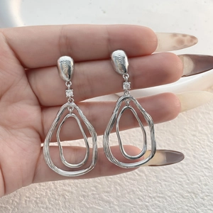 Vue détaillée de boucles d'oreilles argentées en forme de goutte d'eau avec cristaux
