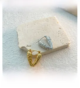 Detailed macro view of gold and silver V-shaped earrings with vintage hammered texture
