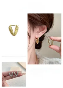 Detailed view of V-shaped gold earrings with hammered texture and geometric vintage style