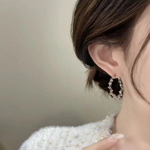 Primo piano di orecchini a cerchio in argento scintillante con cristalli pavé su modella
