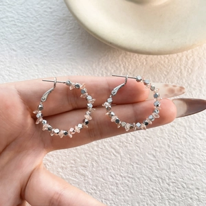 Dettaglio di orecchini a cerchio boho con perle di metallo argento e cristalli rosa