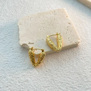Detailed view of gold-plated heart-shaped earrings with unique hammered texture surface