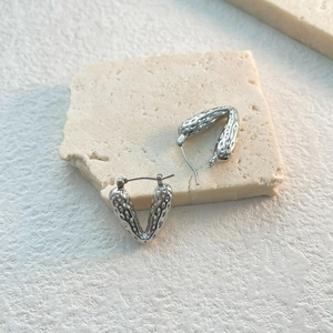 Detailed view of silver heart-shaped earrings with textured hammered finish on stone