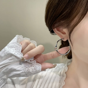 Créoles géométriques irrégulières en argent avec design ondulé poli portées par un mannequin