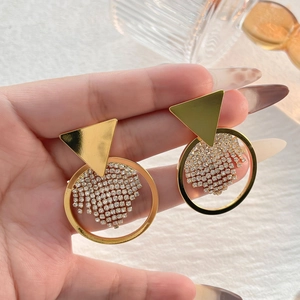 Goldene geometrische Ohrringe mit funkelnden Strass-Quasten in der Hand zur Präsentation