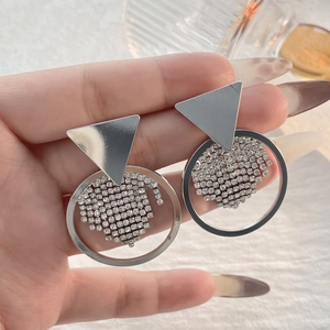 Nahaufnahme geometrischer silberner Ohrstecker mit Kristallen von einem Model gehalten