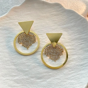 Details goldener geometrischer Dreieck-Ohrringe mit Kristallfransen auf Keramikschale