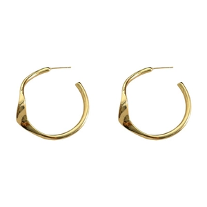 Boucles d'oreilles créoles dorées irrégulières avec lignes ondulées sur fond blanc pur