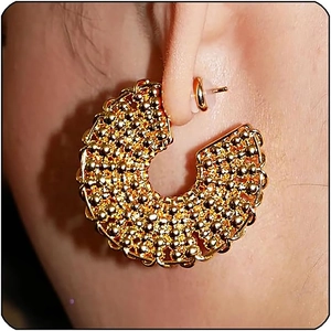 Macro view of gold-plated C-shaped earrings with micro-bead texture on ear lobe