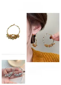 Macro detail of large gold hoop earrings with intricate clustered camellia flower designs