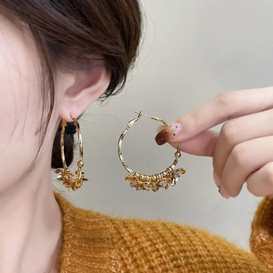 Elegant gold-plated camellia flower hoop earrings worn by a model in yellow knitwear