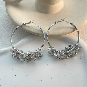 Close-up of silver hoop earrings with floral clusters and sparkling diamond accents