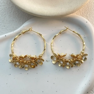 Detailed view of large gold hoop earrings with crystal camellia floral accents