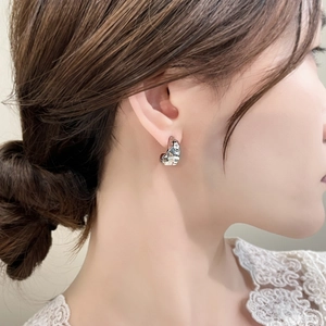 Close-up of minimalist silver irregular textured C-shaped hoop earrings on a model