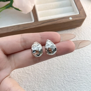 Macro detail of silver-toned hammered teardrop earrings with a textured metallic finish
