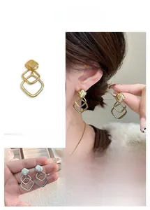 Detail of geometric triple-layered hollow square drop earrings in gold and silver finish