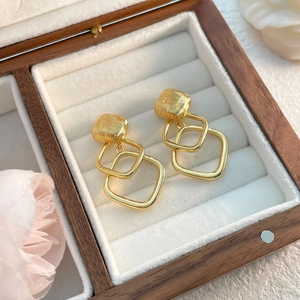 Detail of gold geometric square earrings with brushed texture on a jewelry display