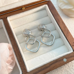 Detailed view of silver geometric earrings with woven texture on velvet padding