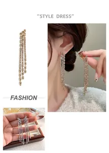 Close-up of long gold-plated chain tassel earrings with shimmering cubic zirconia
