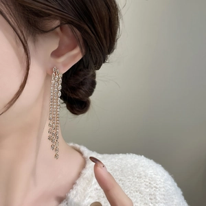 Macro shot of gold tassel earrings with glittering cubic zirconia rows on model