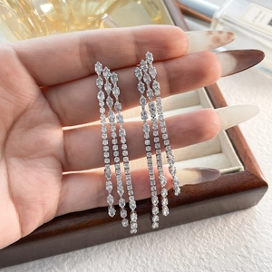 Close-up of elegant long silver tassel earrings with shimmering rows of zircon stones