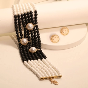 Handmade black and white pearl choker necklace with vintage earrings on white podiums