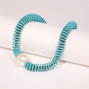 Turquoise disc bead necklace with a large white faux pearl on a minimalist stand